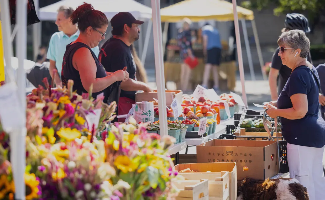 Residents buying produce and flowers at an outdoor market.